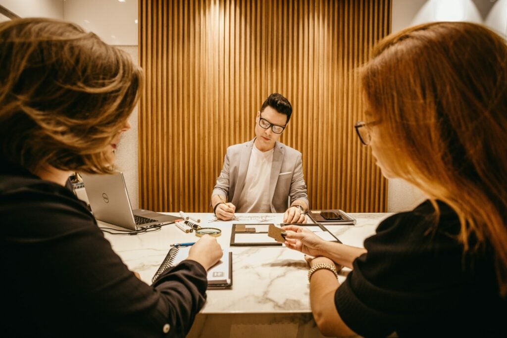 3 people sitting at a boardroom table